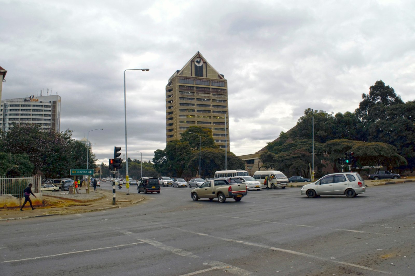 A Harare intersection with kombis and traffic, the NetOne building and the pyramid-topped Karigamombe Centre rising behind